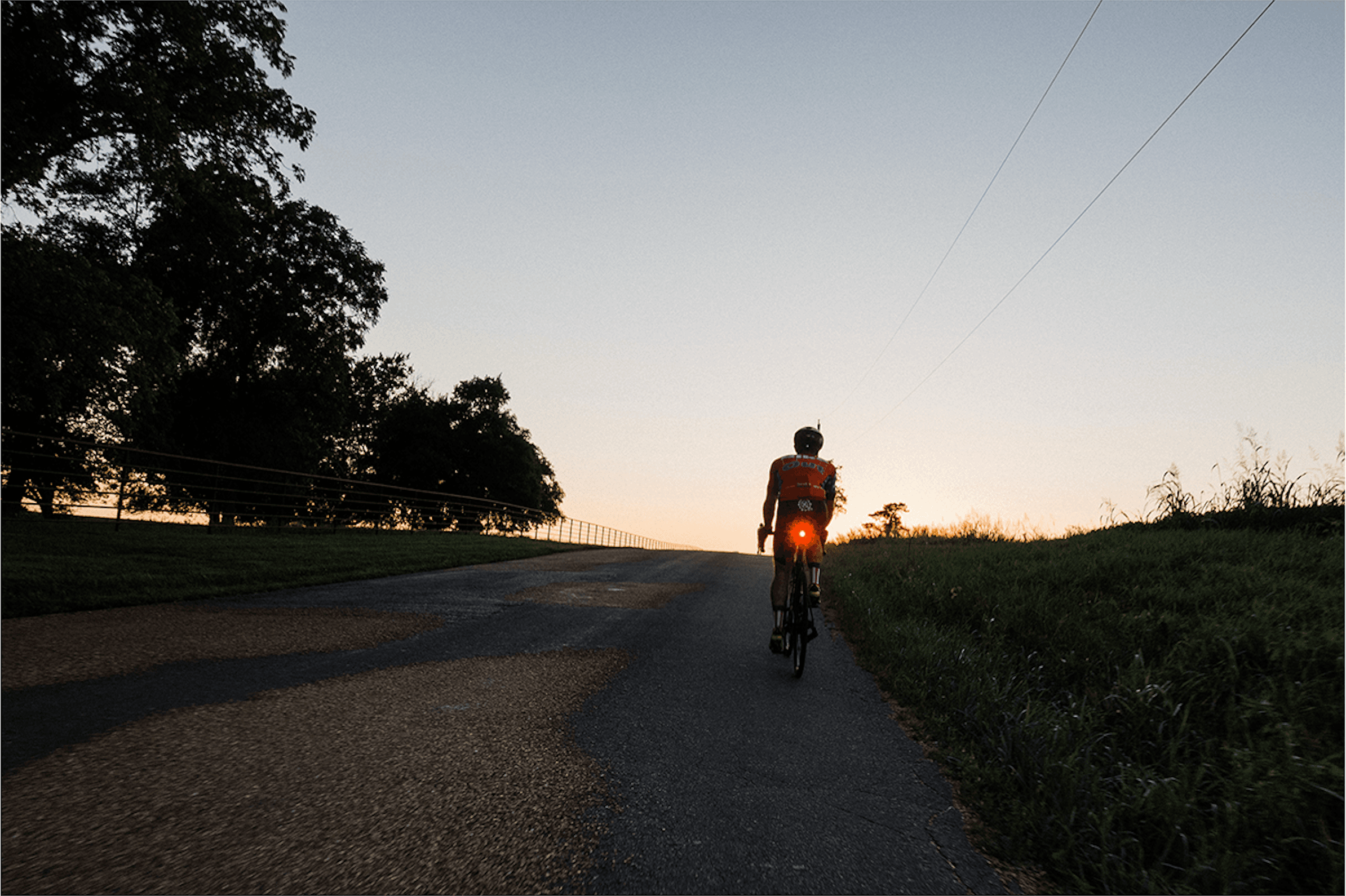 David Forster cycling alone on a country road at sunset